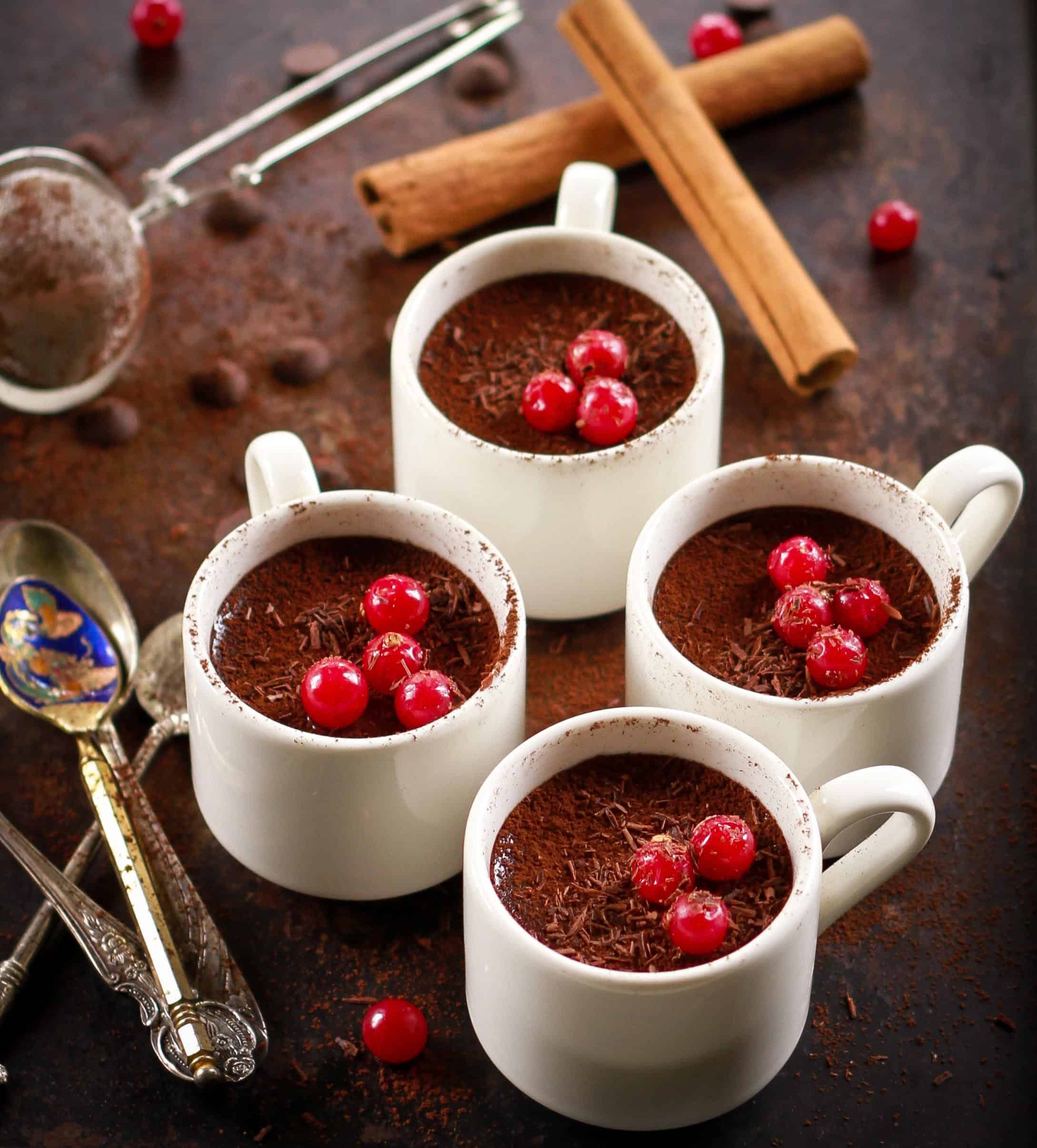 4 white cups with chocolate pudding and berries.