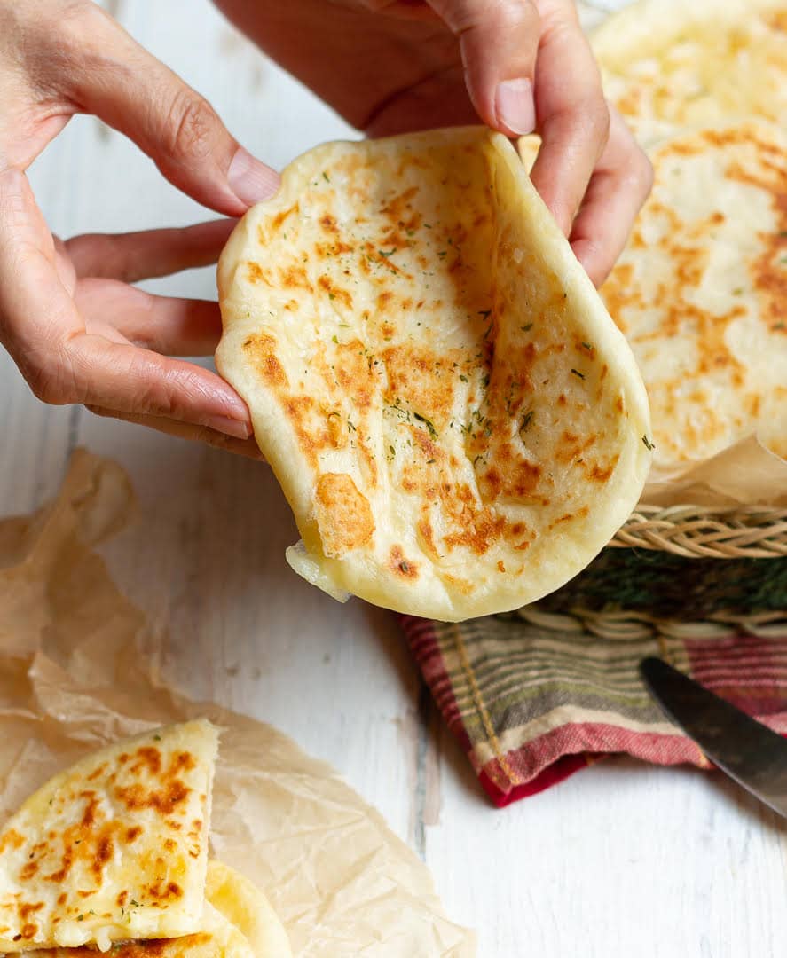 Folding 1 cheese filled flatbread to show its softness.
