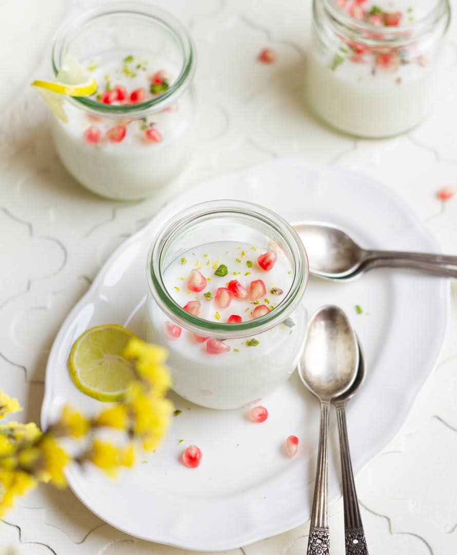 3 jars of lemon panna cotta garnished with pomegranate arils.