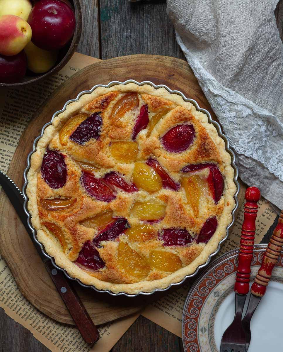 A tart with fruits on a wooden board.