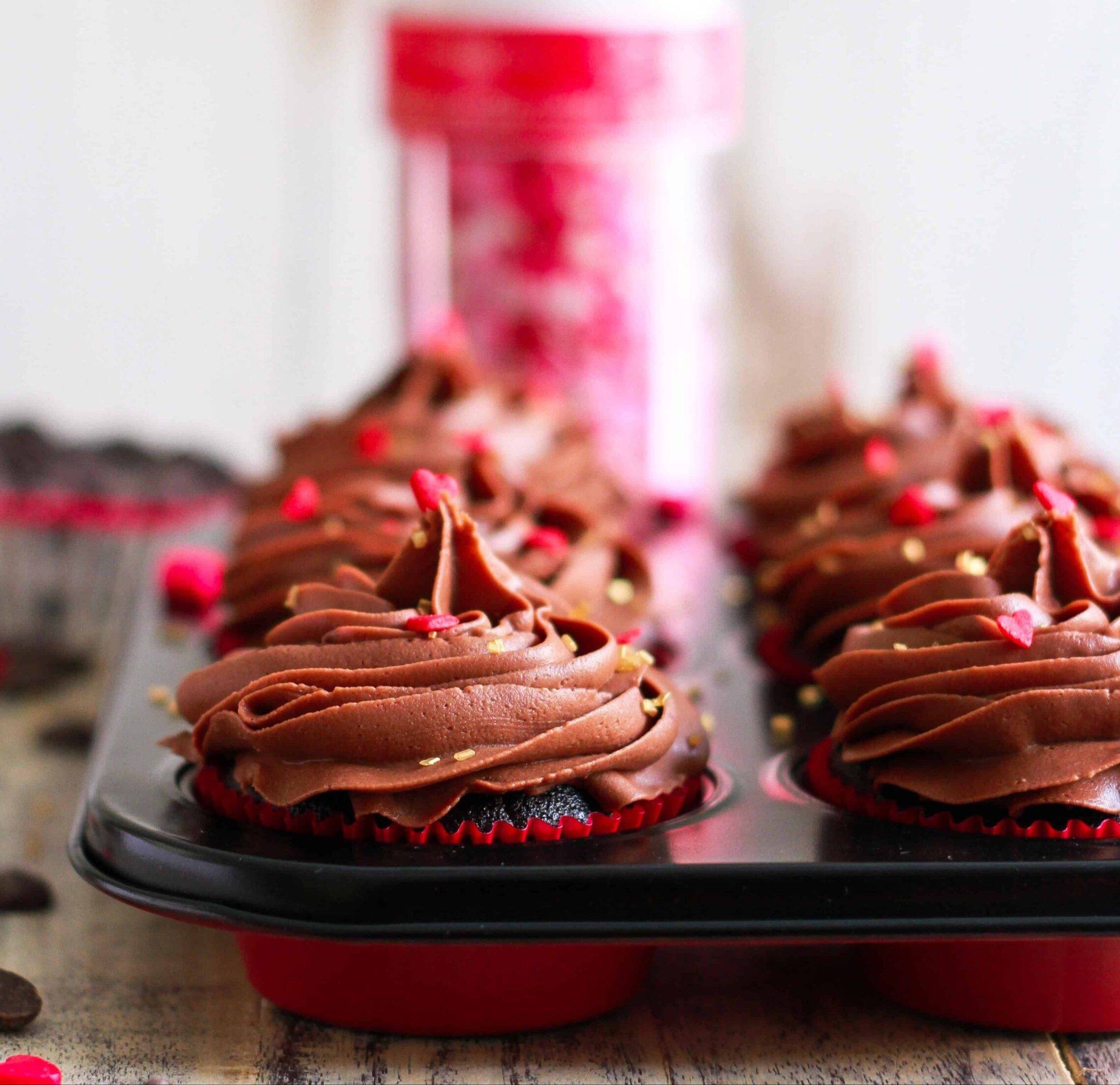 Chocolate cupcakes with frosting in a muffin tray.