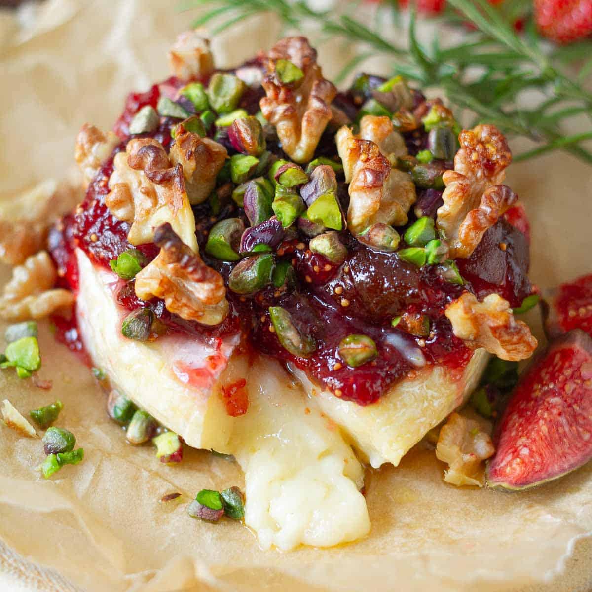 Melting baked brie topped with fig jam and nuts.