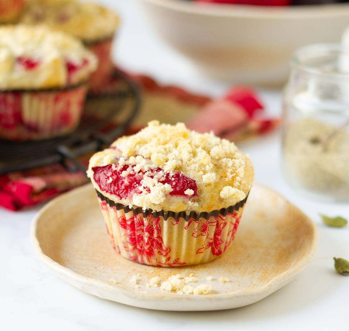 A plum muffin with streusel on a small plate.