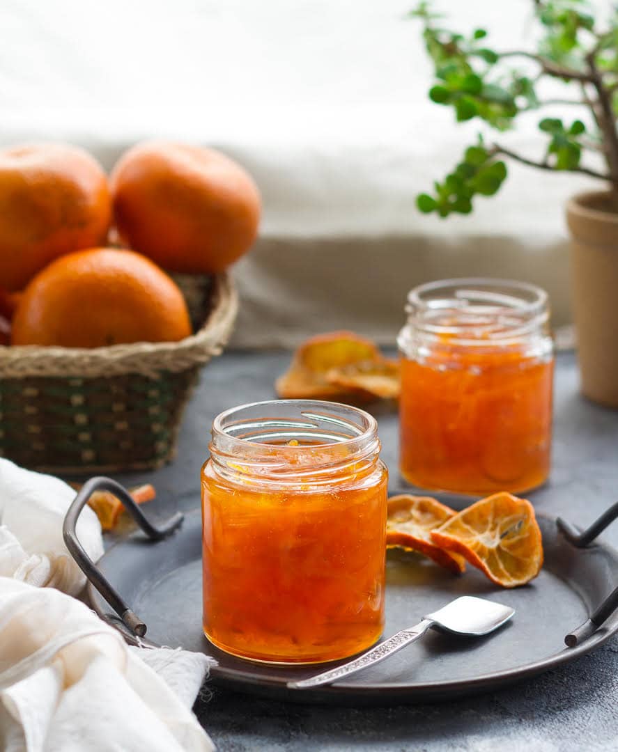 2 jars of orange marmalade on a gray plate.