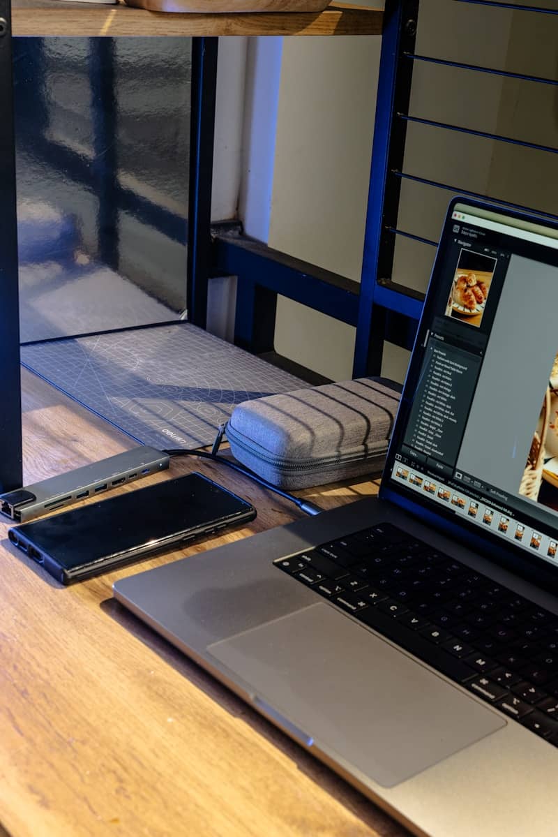Laptop, phone, and hub on a wooden desk.