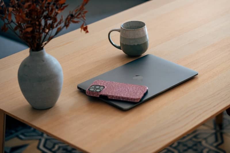 Laptop, phone, and mug on a wooden table.
