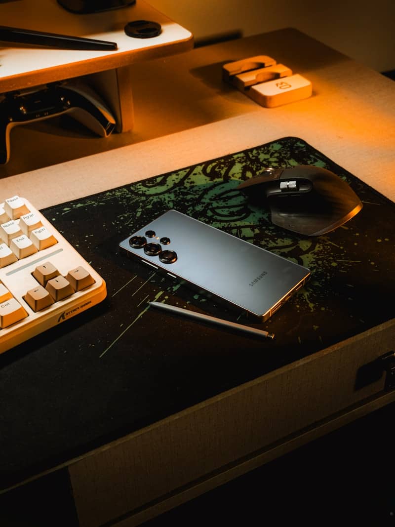 Smartphone and stylus on a desk with keyboard and mouse