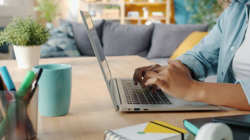 Person typing on a laptop at a wooden desk.