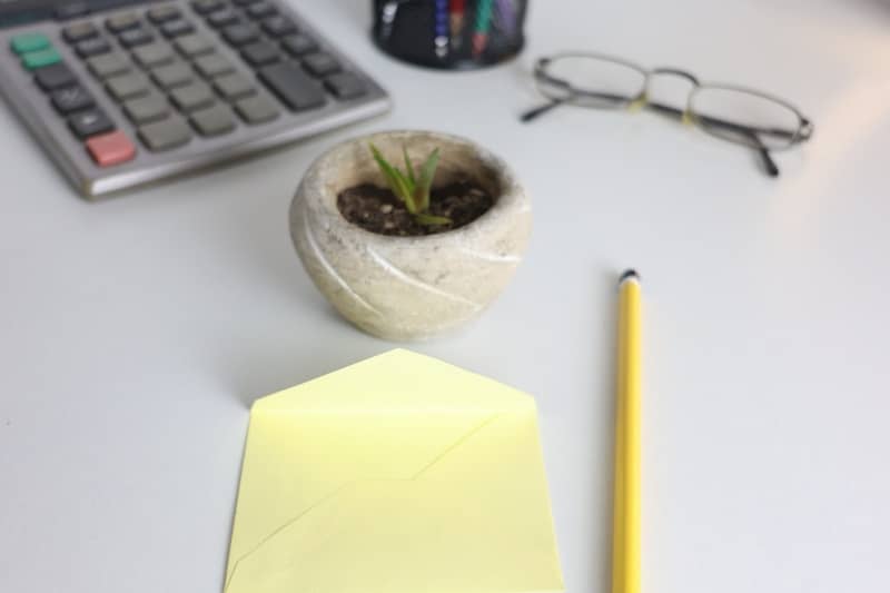 Desk with calculator, plant, glasses, and pencil.