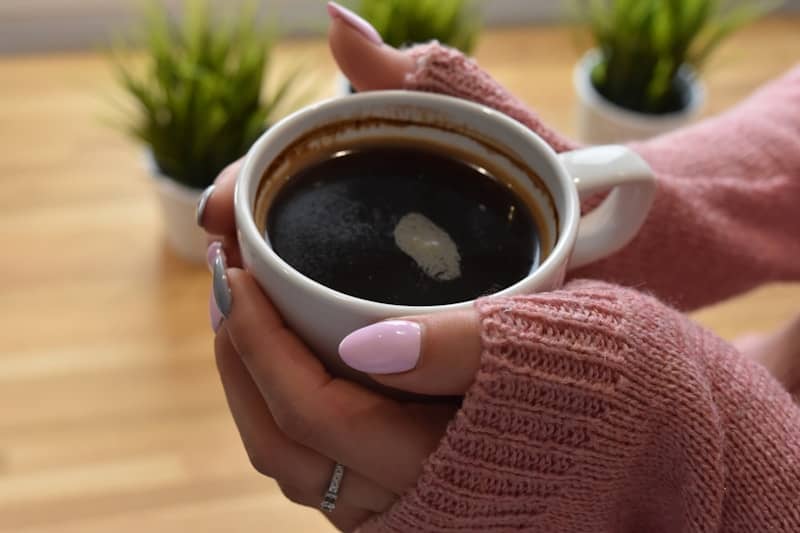 Hands holding a warm cup of black coffee