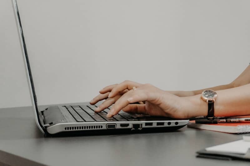 Hands typing on a laptop keyboard with a watch.