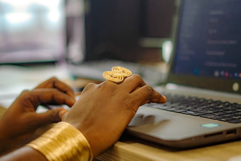 Hands typing on a laptop with gold jewelry