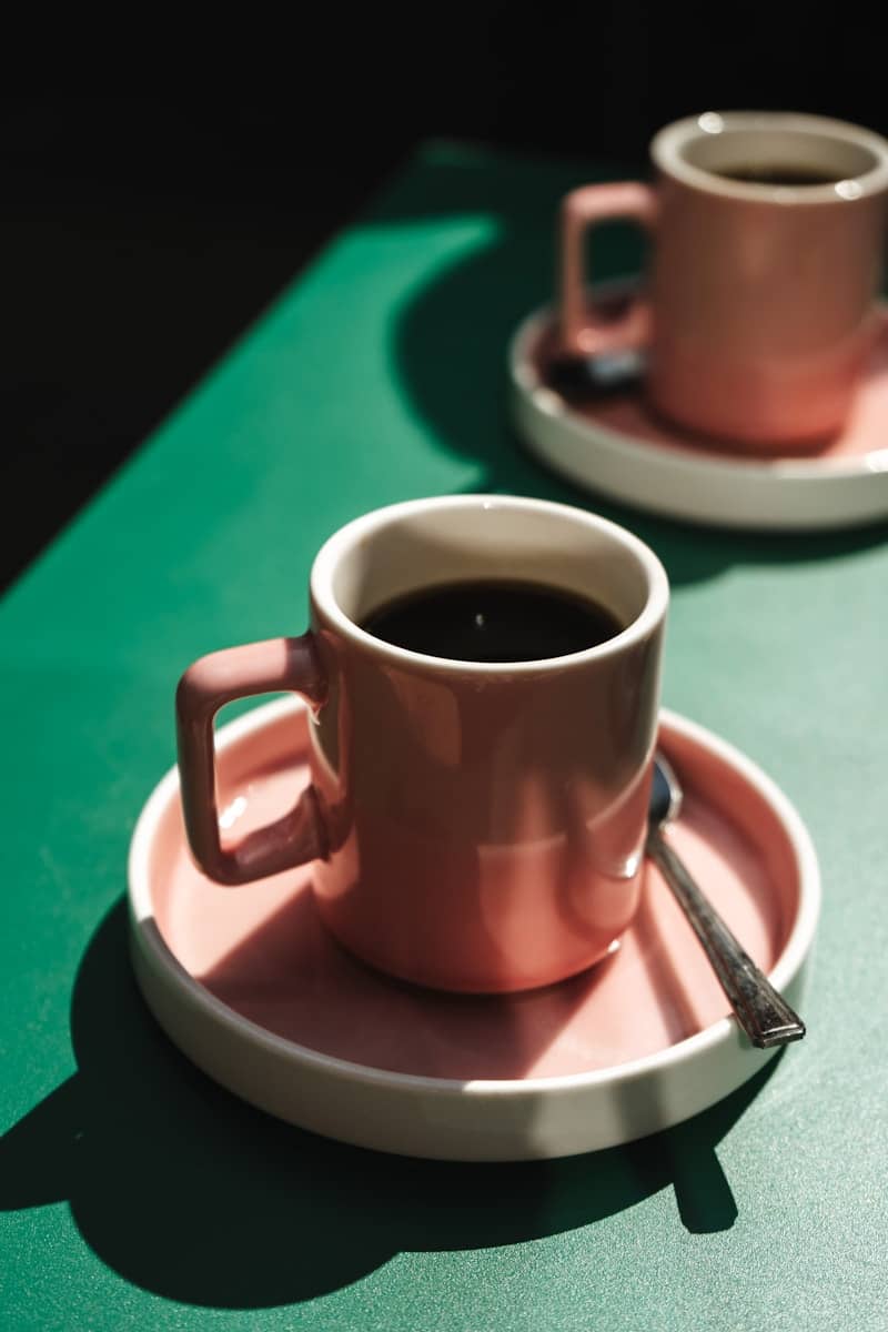 Two pink mugs of coffee on saucers