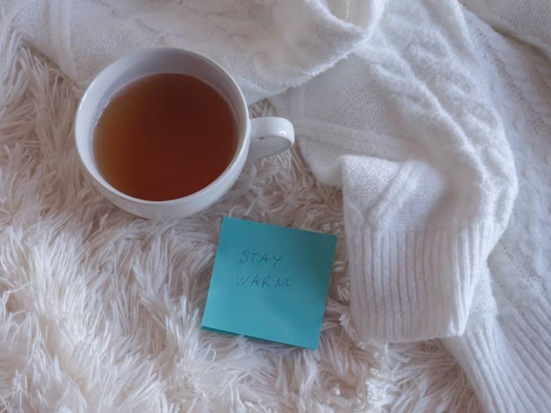 A warm cup of tea next to a cozy sweater