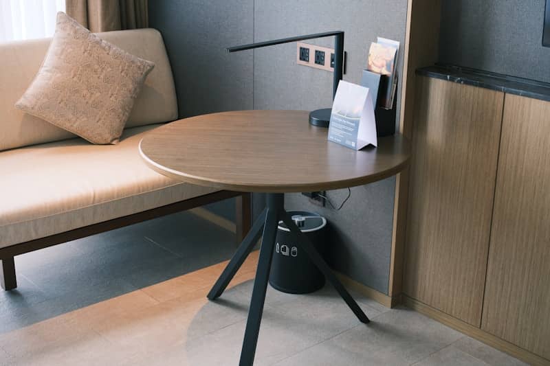 Round wooden table with modern lamp and sofa.