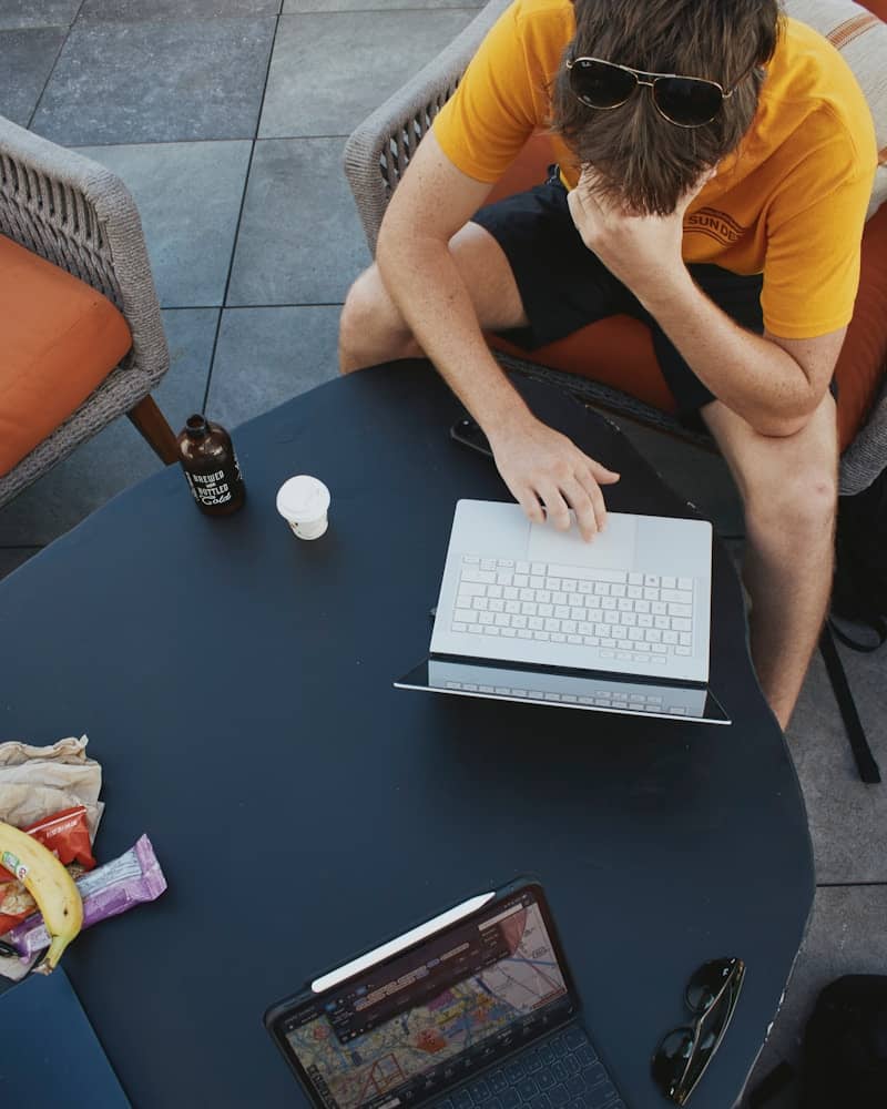Man working on laptop at outdoor table with snacks