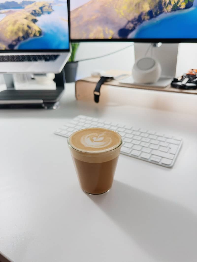 Latte art coffee on a desk with computer monitors
