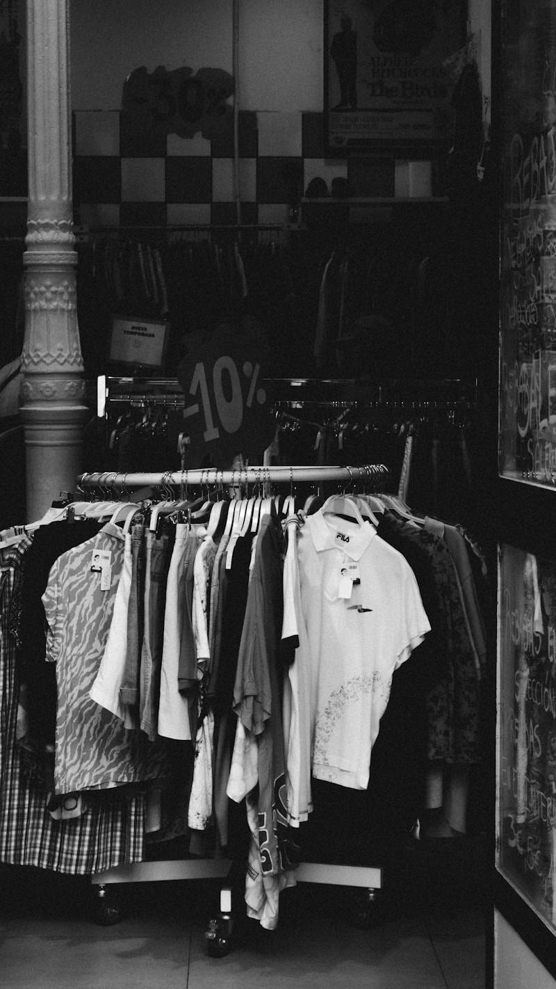 Clothing rack with various shirts and dresses on display.