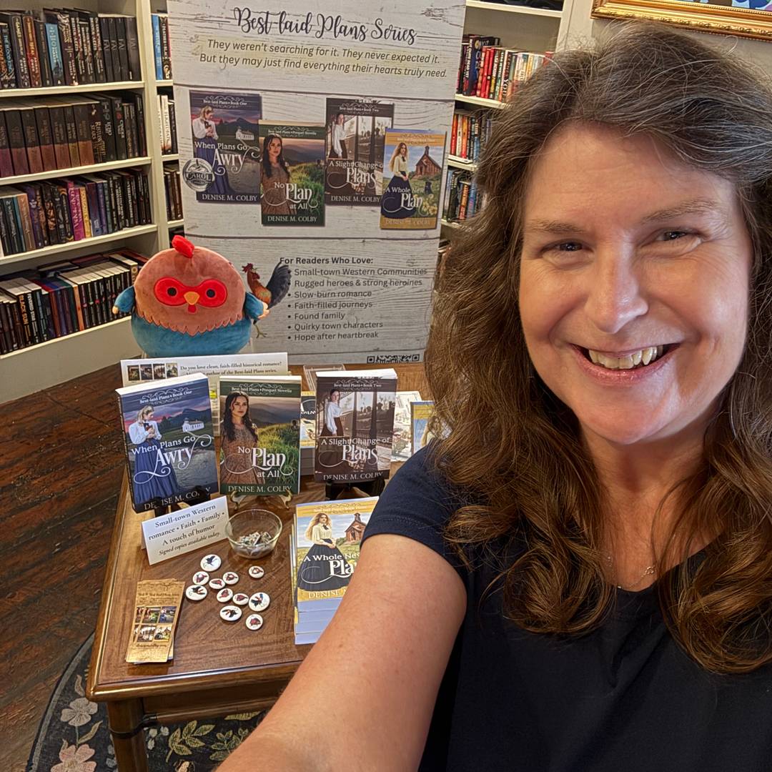 Denise M. Colby with her book signing table inside In Bloom Bookery