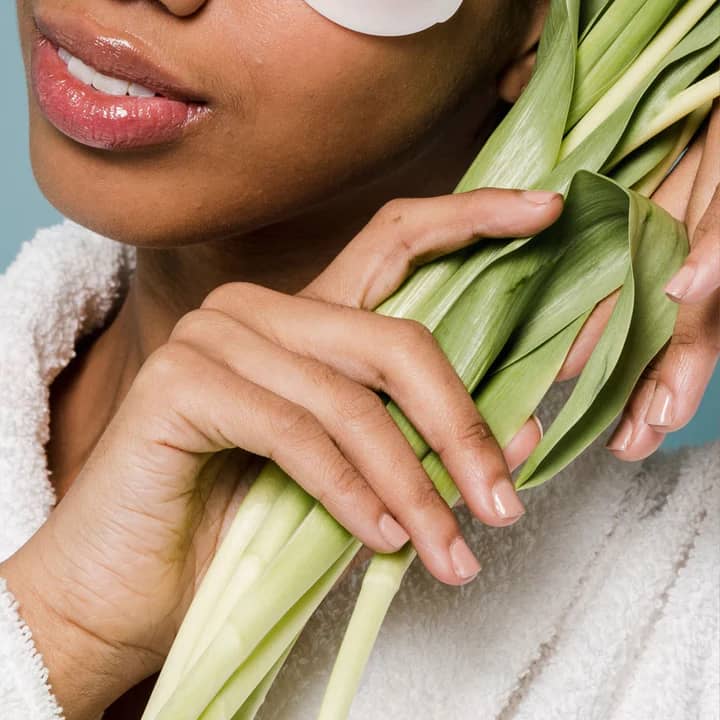 A woman gently holding a bamboo shaft next to her face, symbolizing natural beauty and holistic skincare supported by collagen.