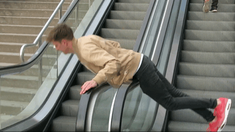Man stuck on railing of escalators spinning around and struggling to get off