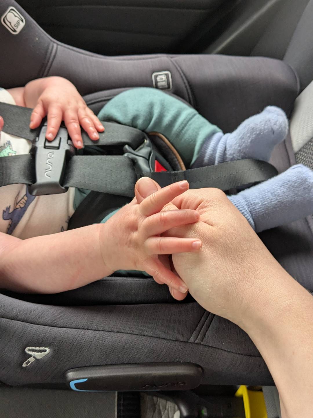 A newborn holding onto a woman's hand.