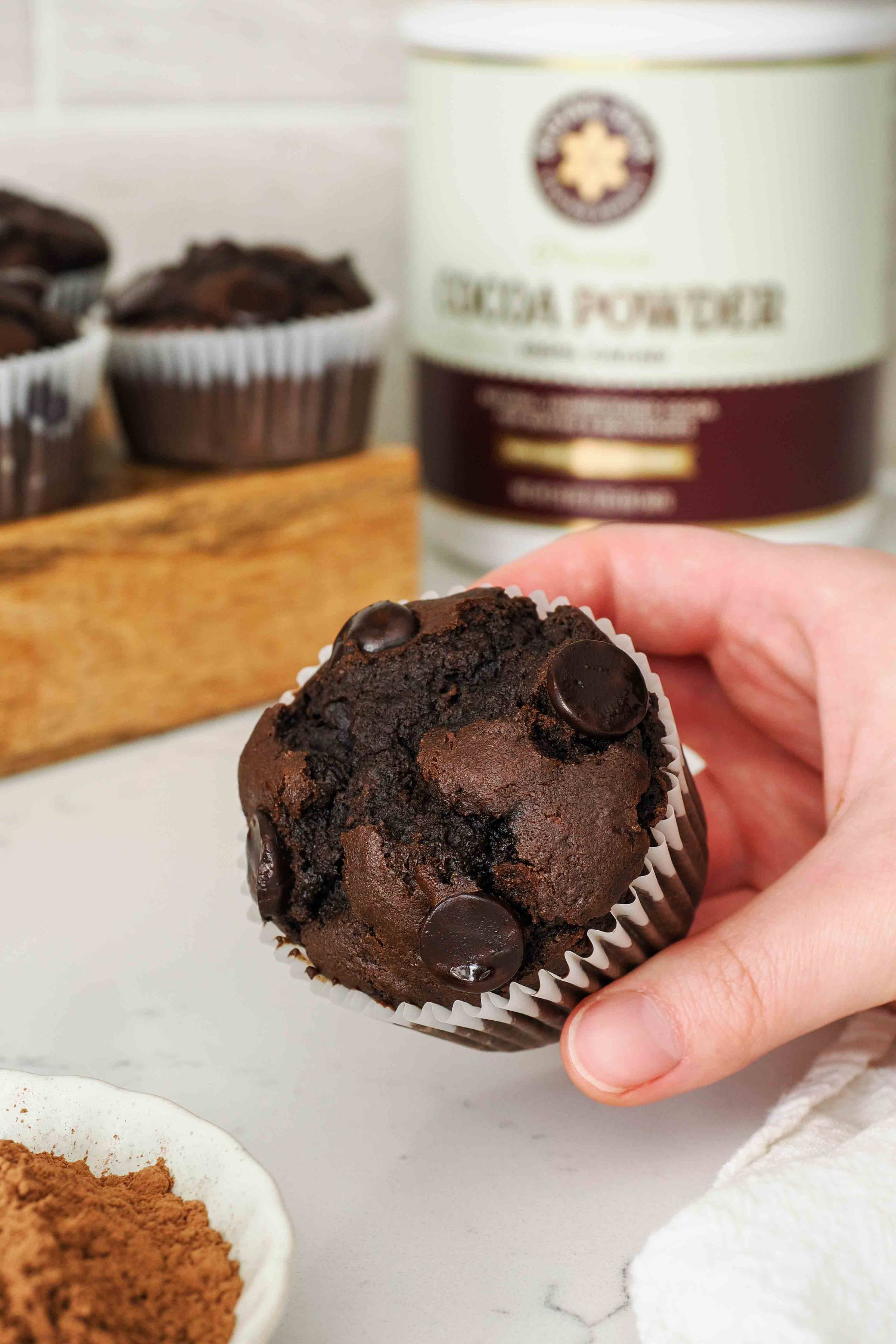 A hand holds a chocolate muffin