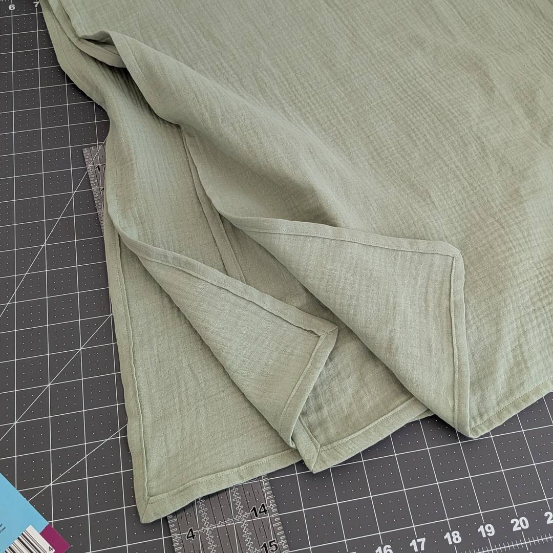 Four mitered corners on a green muslin blanket