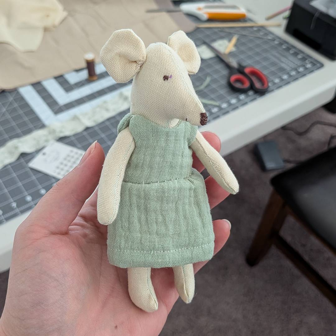 A fabric toy mouse wearing a green dress.