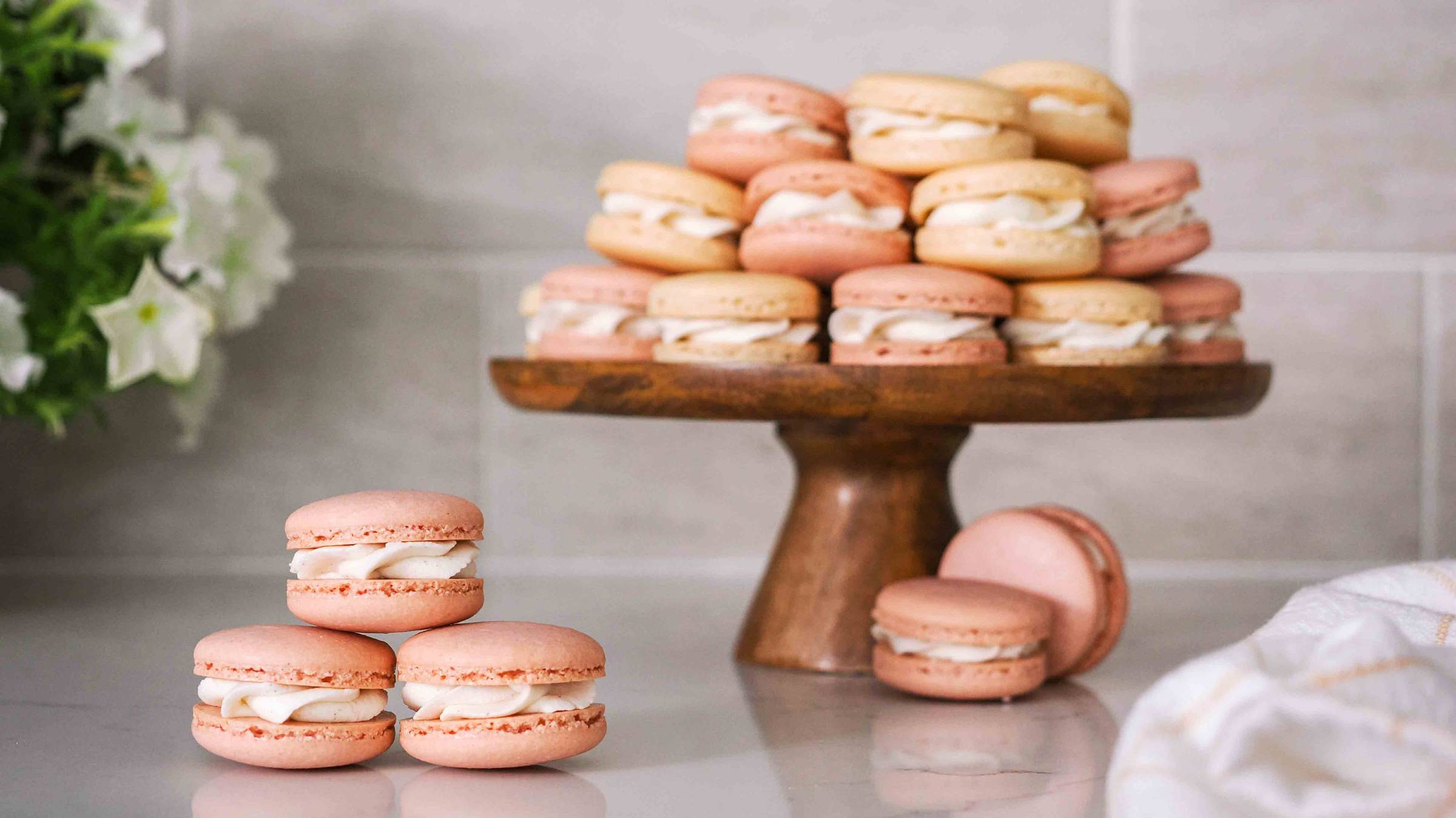 A stack of vanilla macarons on a small cake stand.