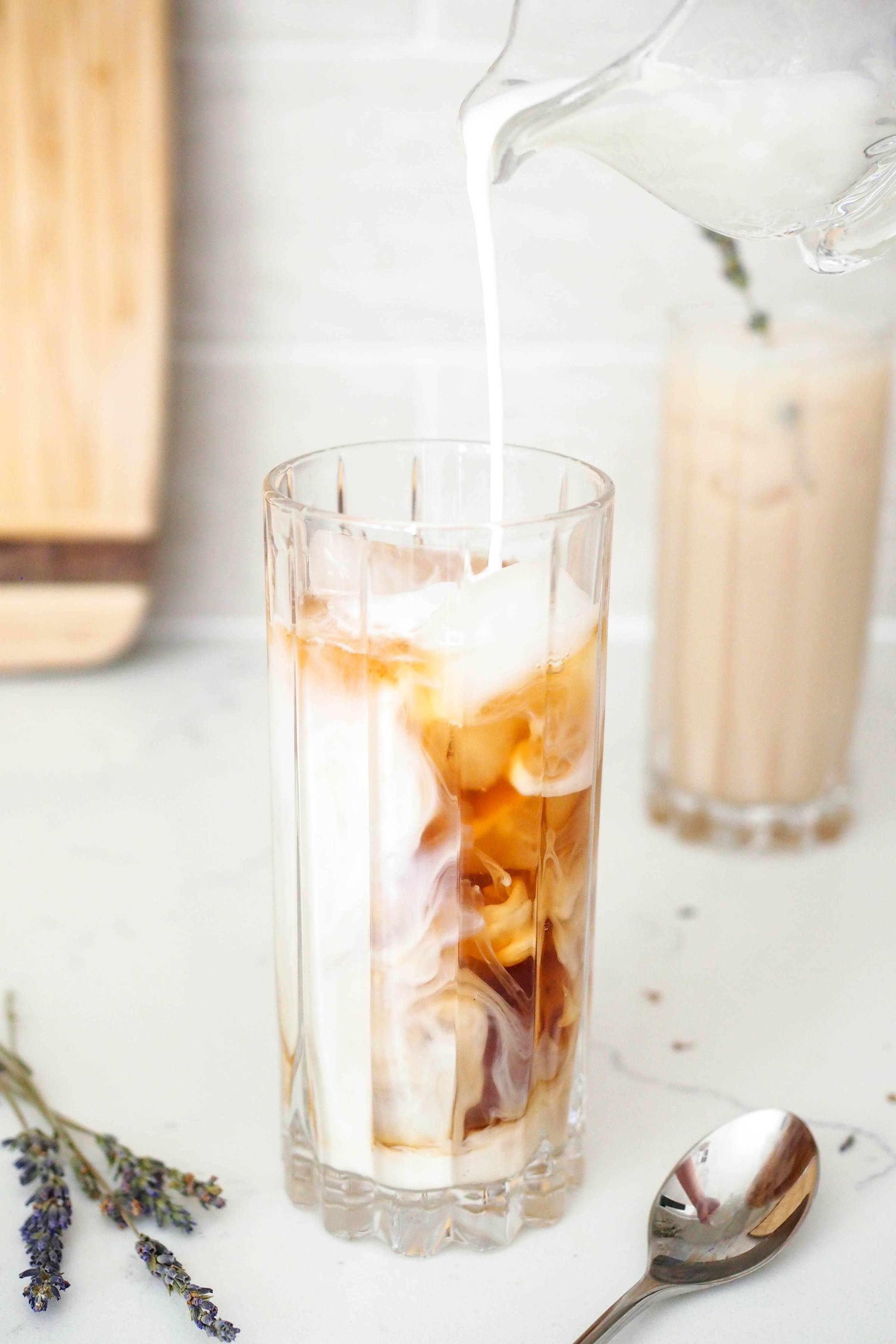 Milk is poured into a glass of iced tea.
