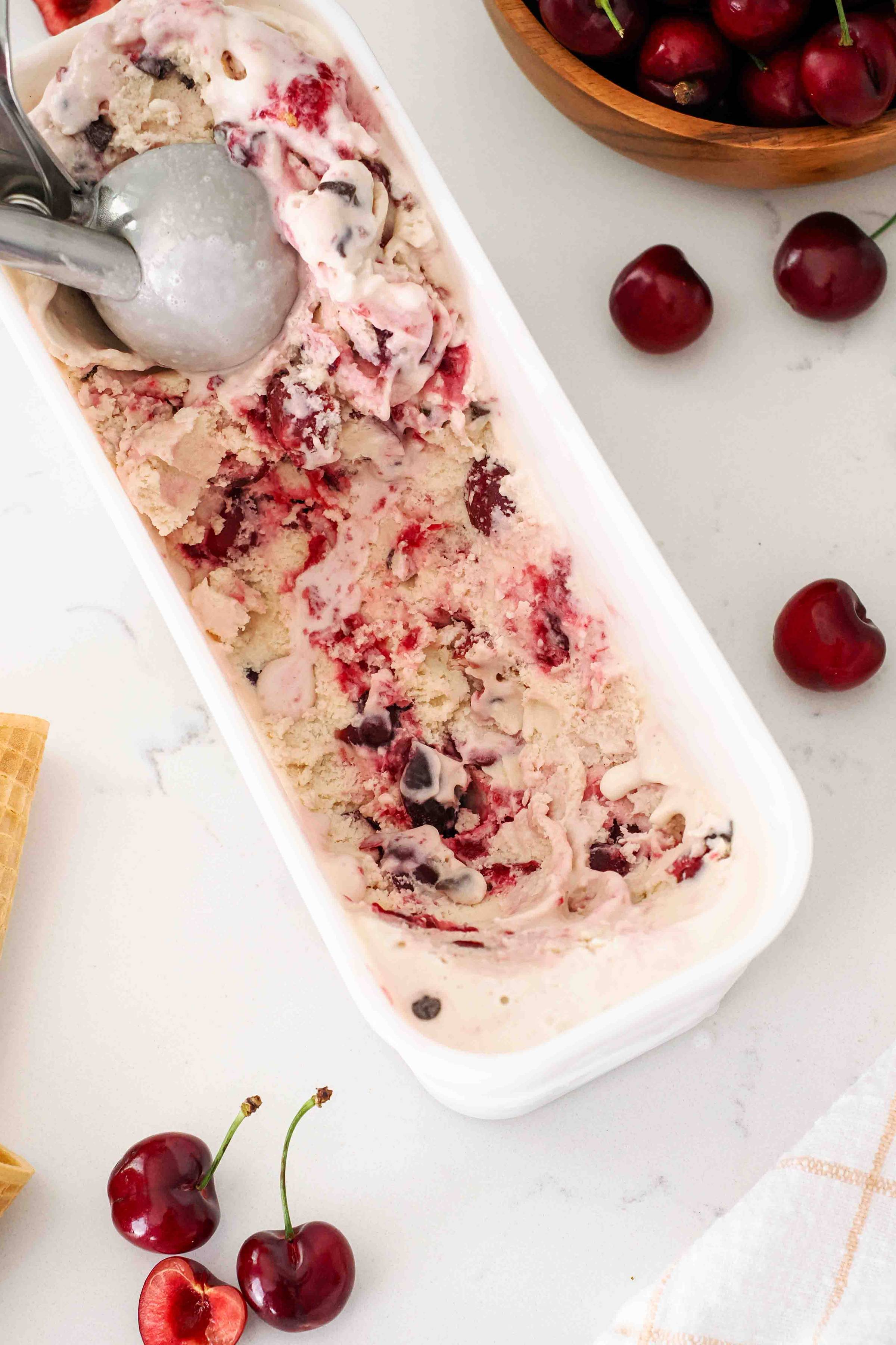 A container of vanilla ice cream with cherry swirls