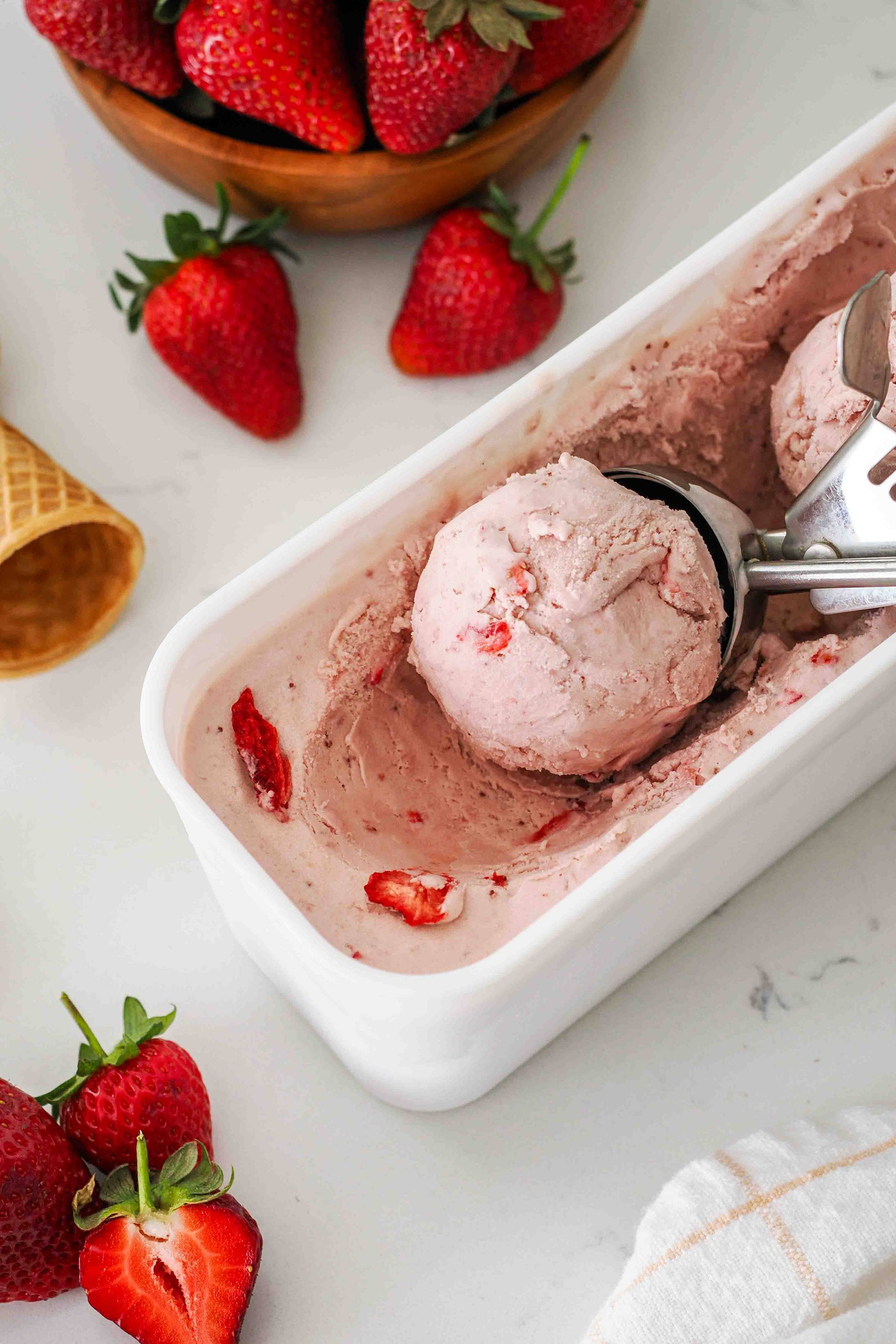 A scoop of strawberry ice cream near strawberries