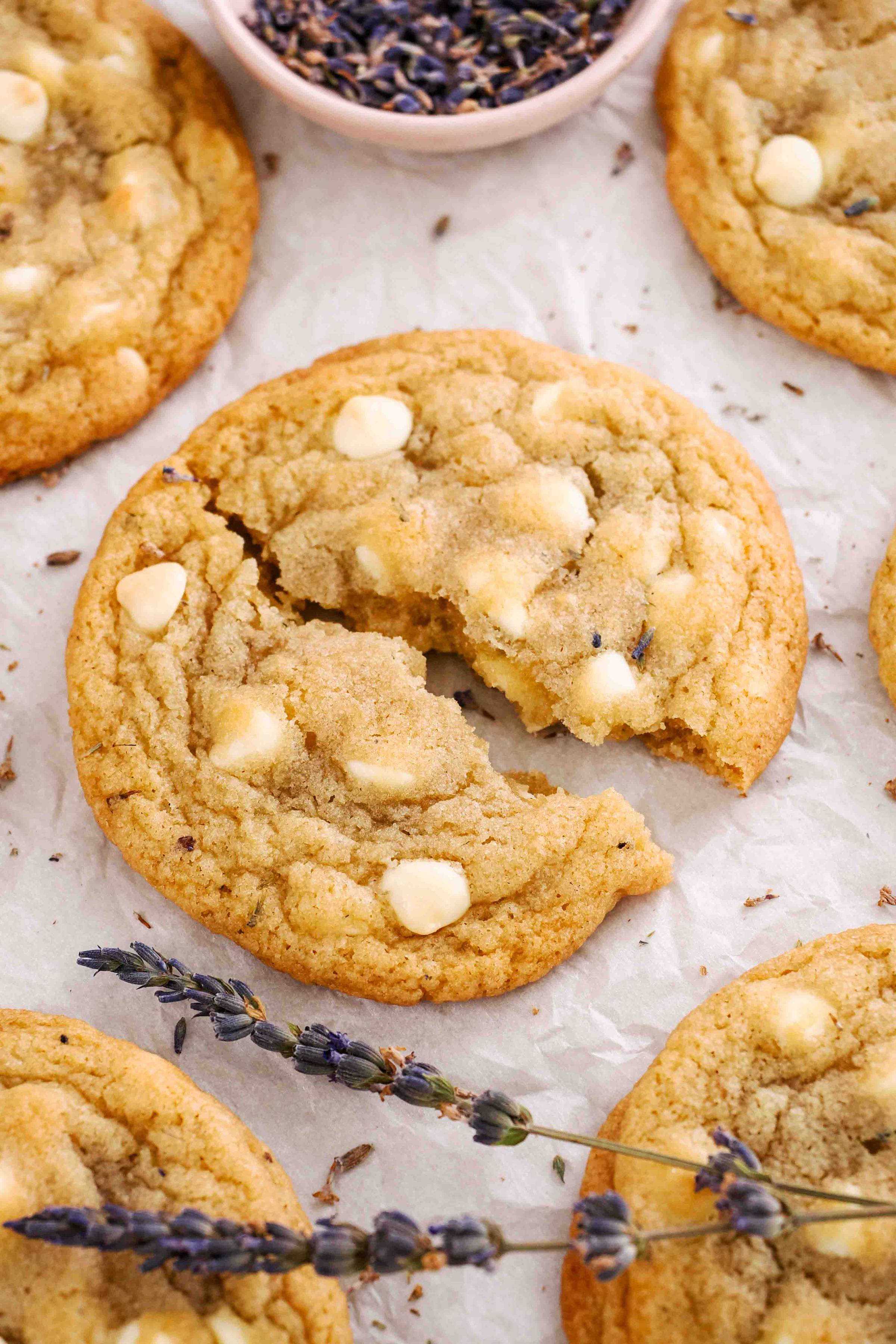 A white chocolate chip cookie on parchment with lavender.
