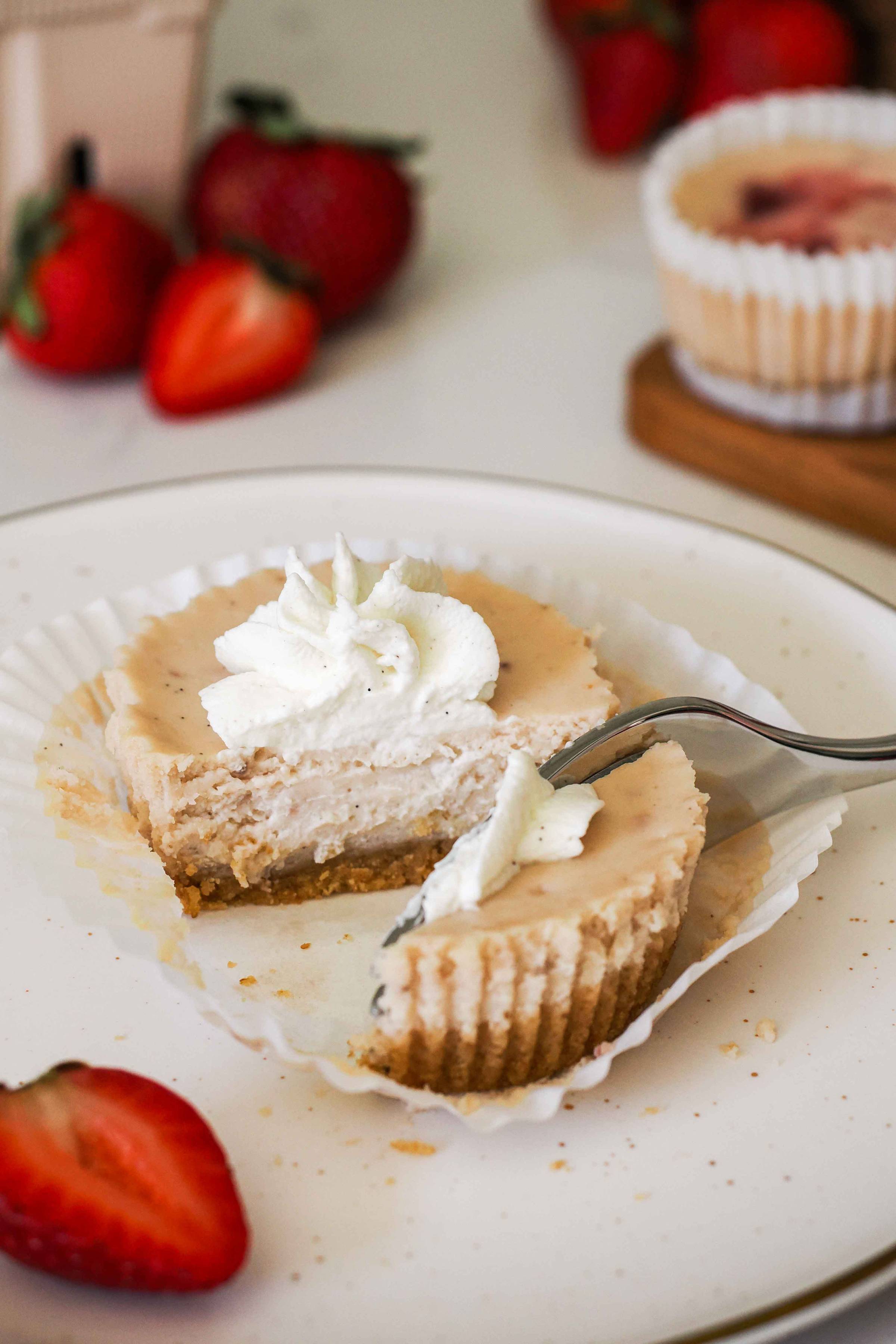 A mini strawberry cheesecake cut in half with a fork