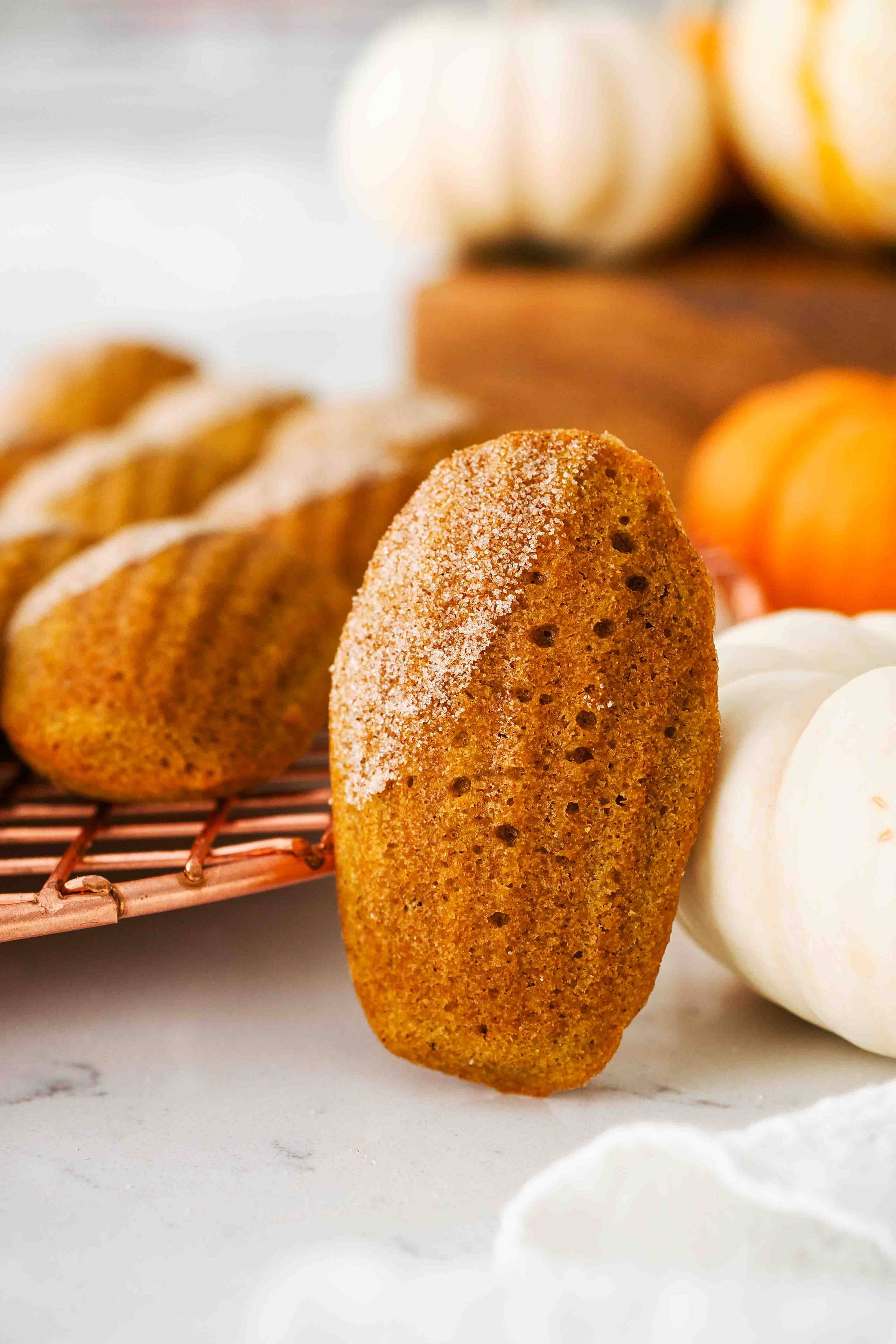 A pumpkin madeleine leans against a white mini pumpkin.