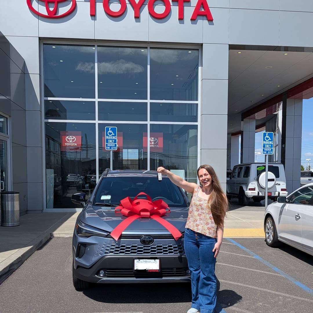 Alyssa holding the keys in front of a car with a red bow on it.