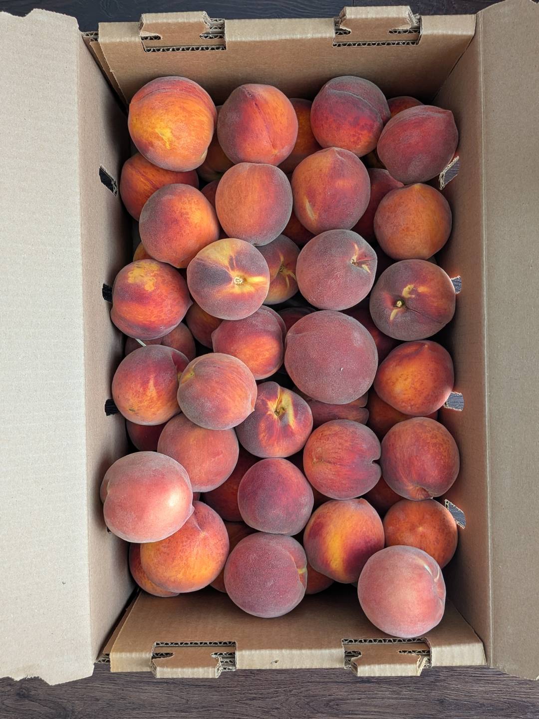 A cardboard box with 20 lbs of peaches