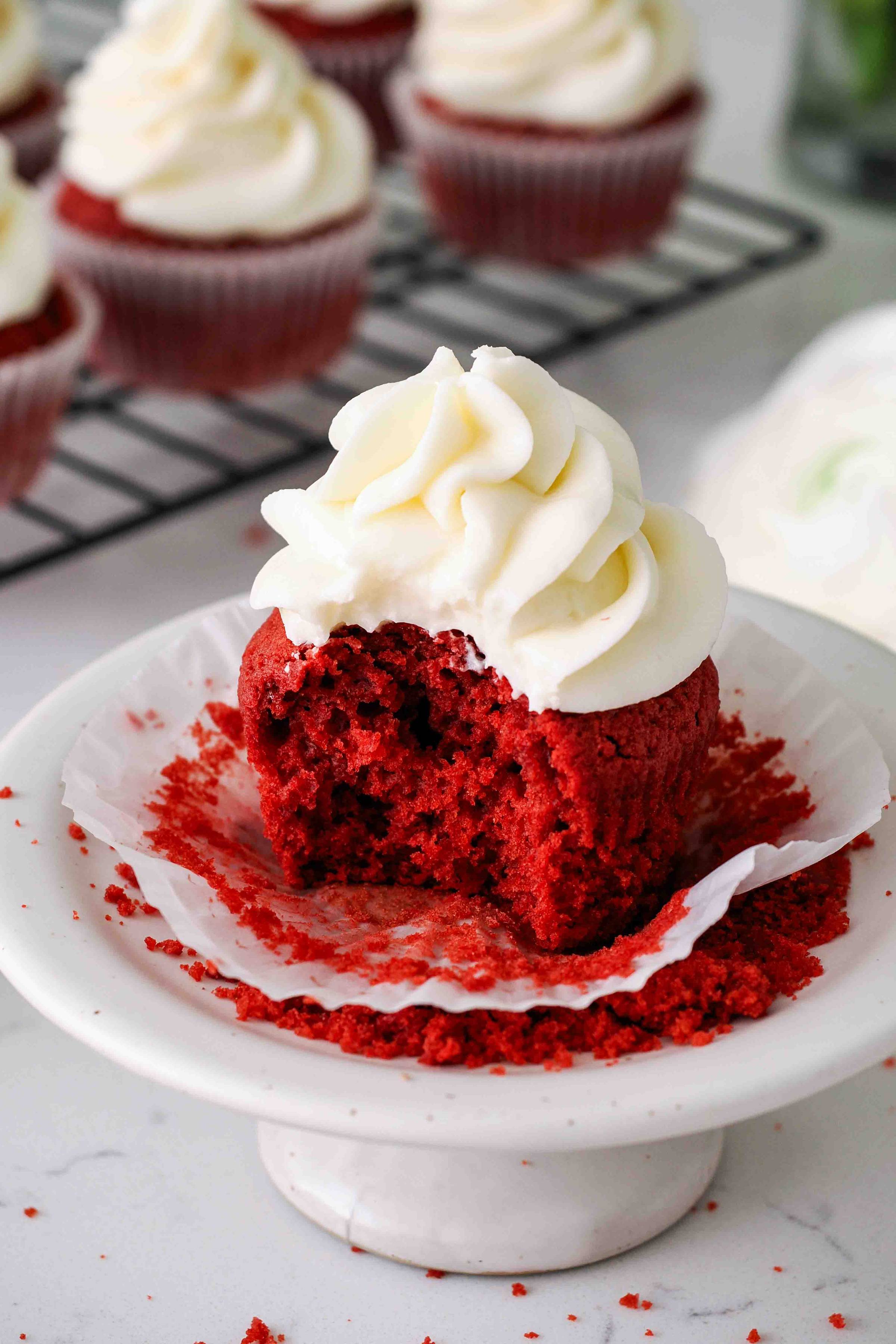A bite taken out of a red velvet cupcake.