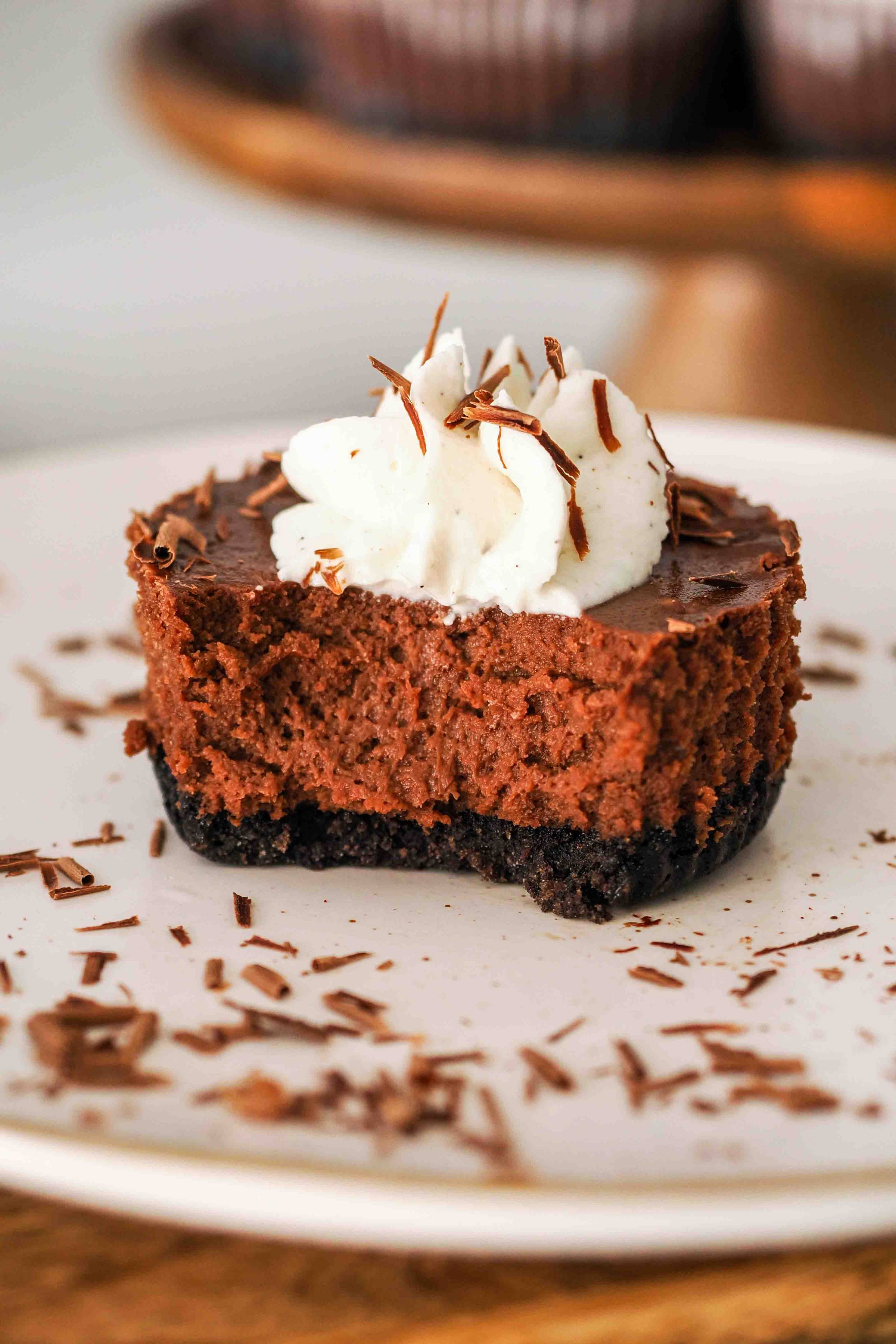 A bite missing from a mini dark chocolate cheesecake