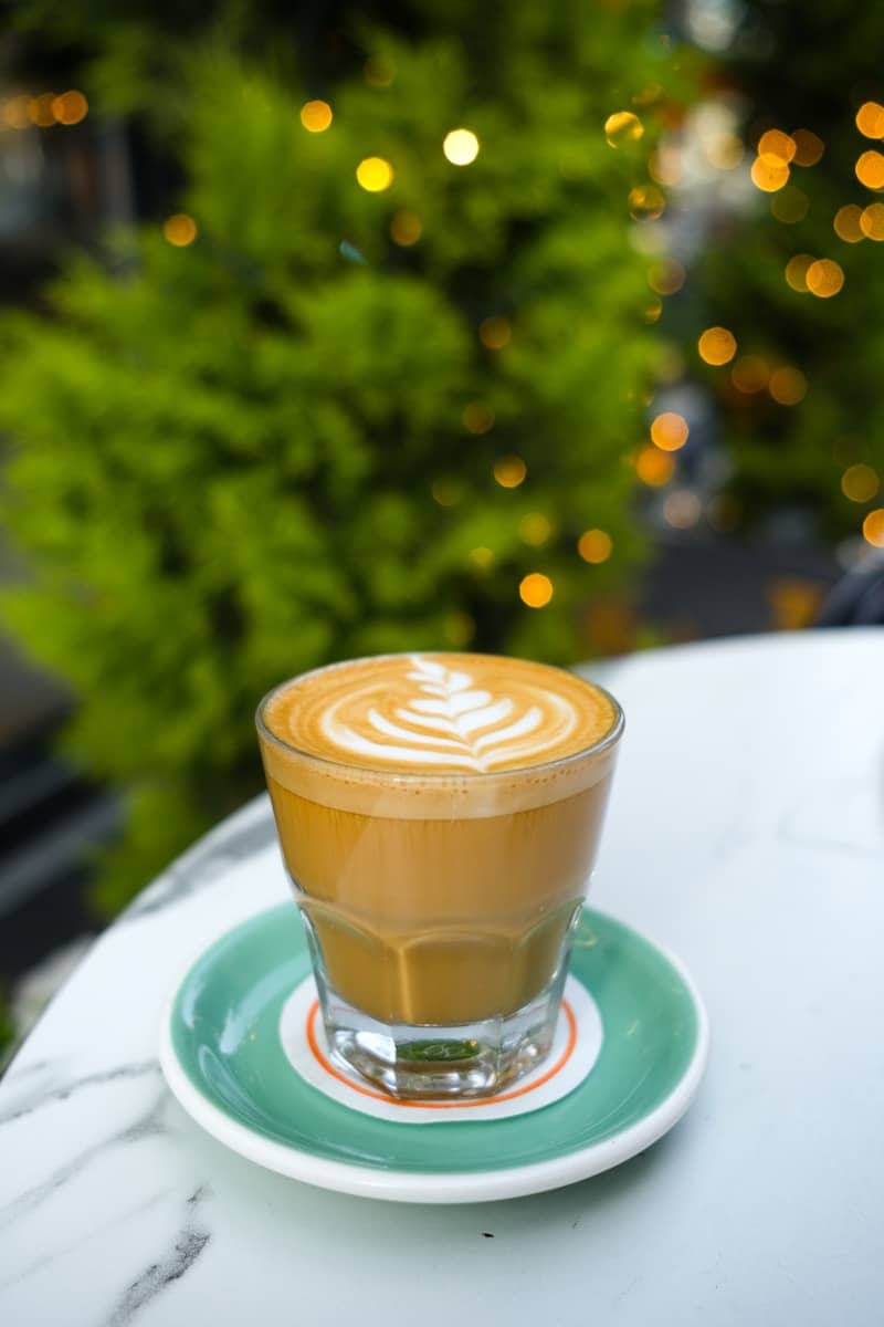 A latte with intricate foam art sits on a saucer.