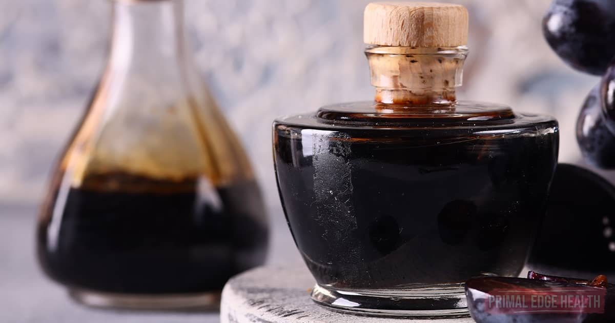 A small glass container of balsamic glaze with a cork stopper.