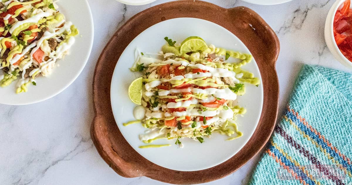 Keto tostada with all the toppings on a white plate on marble surface.