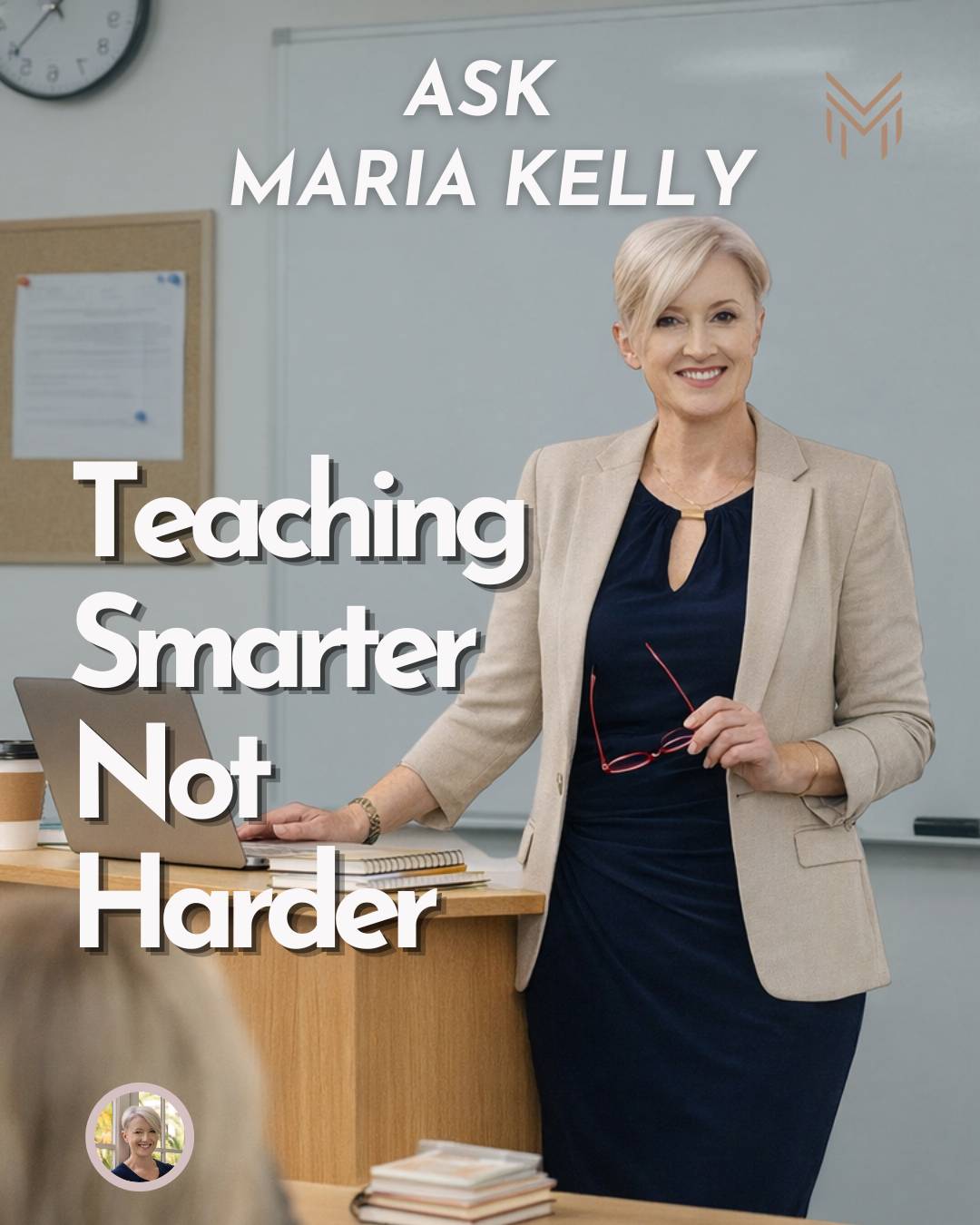 A woman with short blonde hair, a navy dress and beige suit jacket, standing in front of a class holding her glasses in her hand with a desk and a laptop in front of her. She's teaching in class. 