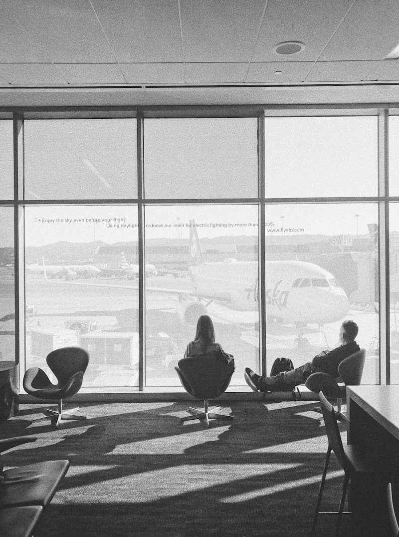 A black and white photo of people sitting in an airport