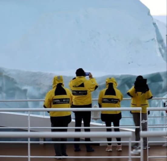 a group of people in yellow jackets standing on a boat