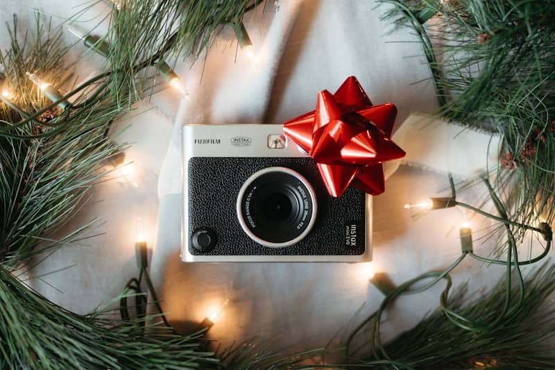 A christmas tree with a camera and a red bow