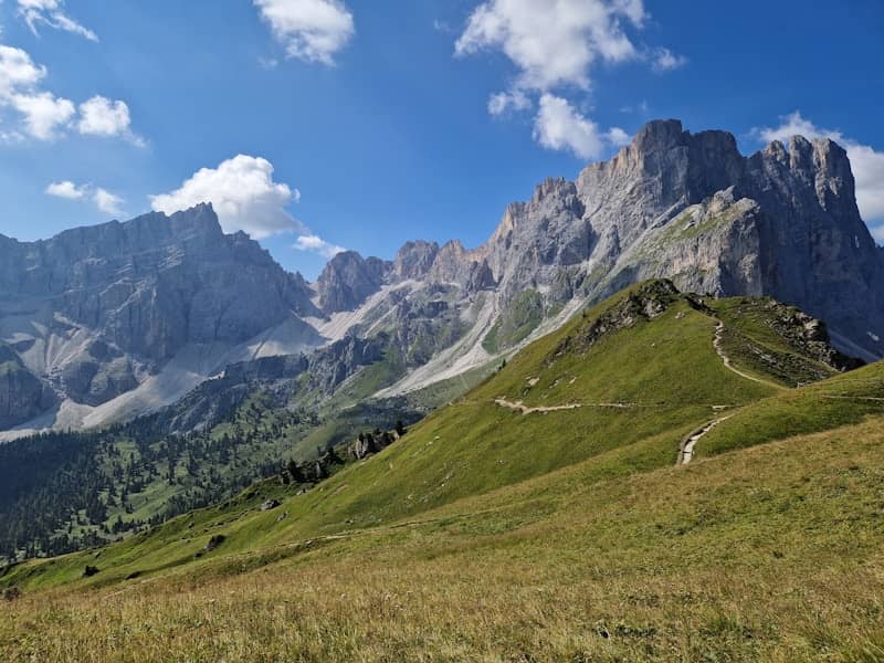 Mountains and green meadows under a bright blue sky.
