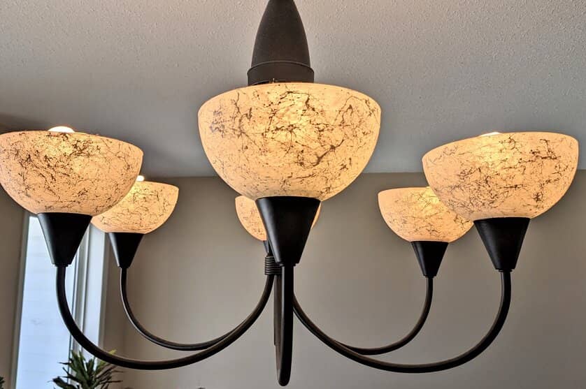 A pretty black and frosted glass chandelier lit.
