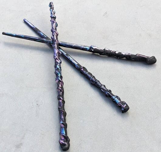 Three black wands displayed on a grey background.
